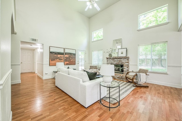 living room with baseboards, visible vents, light wood-type flooring, and a towering ceiling
