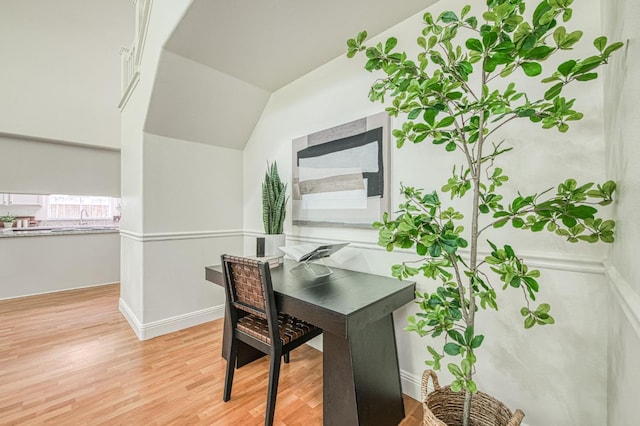 office area featuring light wood-style floors, baseboards, and lofted ceiling