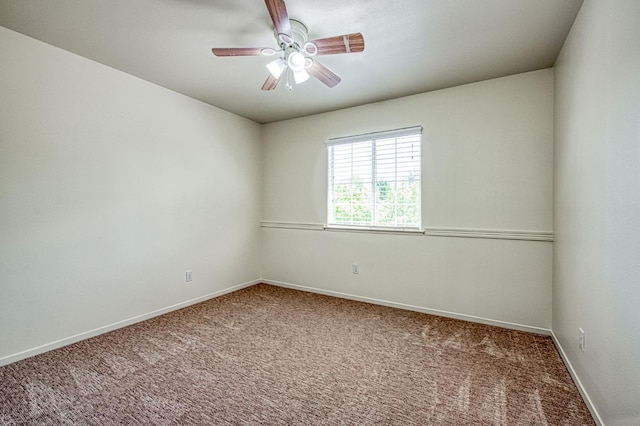 carpeted empty room with a ceiling fan and baseboards