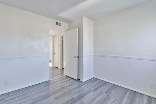 empty room featuring baseboards, wood finished floors, and visible vents