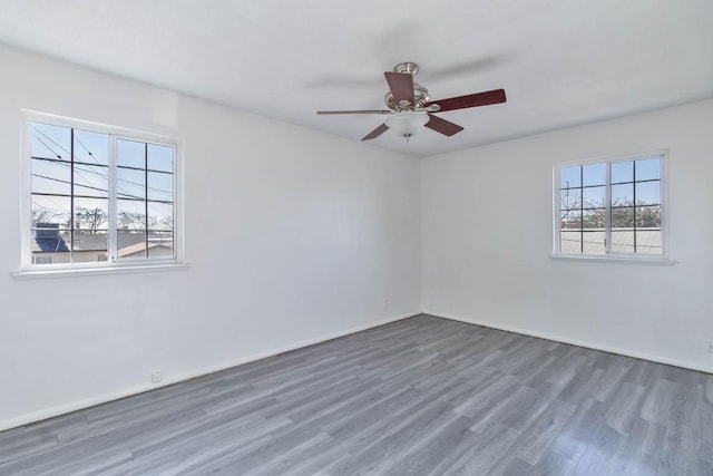 empty room with baseboards, a ceiling fan, and wood finished floors