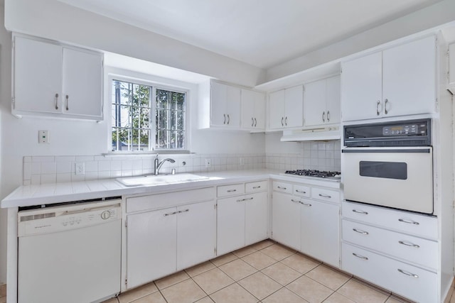 kitchen featuring white appliances, backsplash, a sink, and light countertops