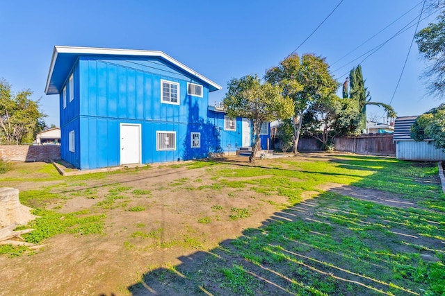 back of property featuring an outbuilding, board and batten siding, fence, and a yard