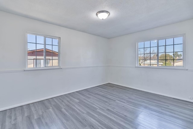 empty room featuring baseboards, a textured ceiling, and wood finished floors