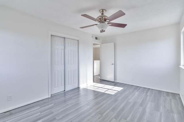 unfurnished bedroom with baseboards, visible vents, wood finished floors, and a closet