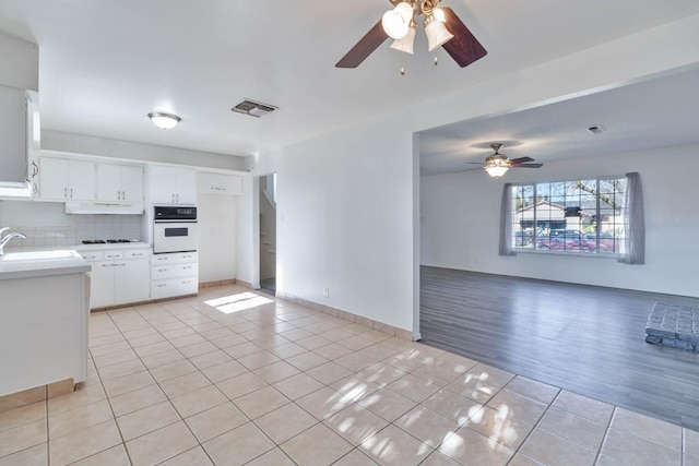 kitchen featuring light tile patterned flooring, ceiling fan, gas cooktop, visible vents, and white oven
