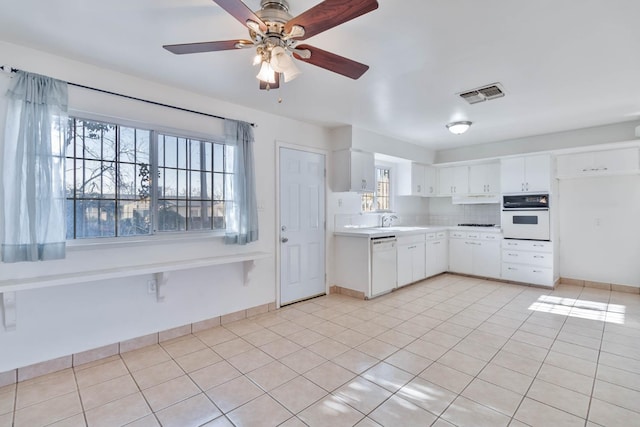 kitchen with visible vents, a ceiling fan, white appliances, light countertops, and a sink