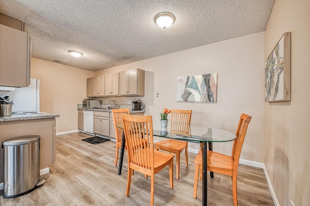 dining space featuring light wood-type flooring, a textured ceiling, baseboards, and visible vents