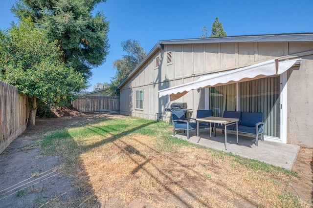 back of property featuring a yard, a patio, board and batten siding, and a fenced backyard