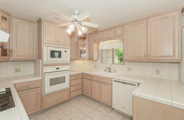 kitchen featuring a sink, light brown cabinets, white appliances, and tasteful backsplash