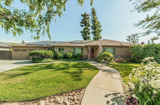 ranch-style house with a garage, stucco siding, a front yard, roof mounted solar panels, and concrete driveway