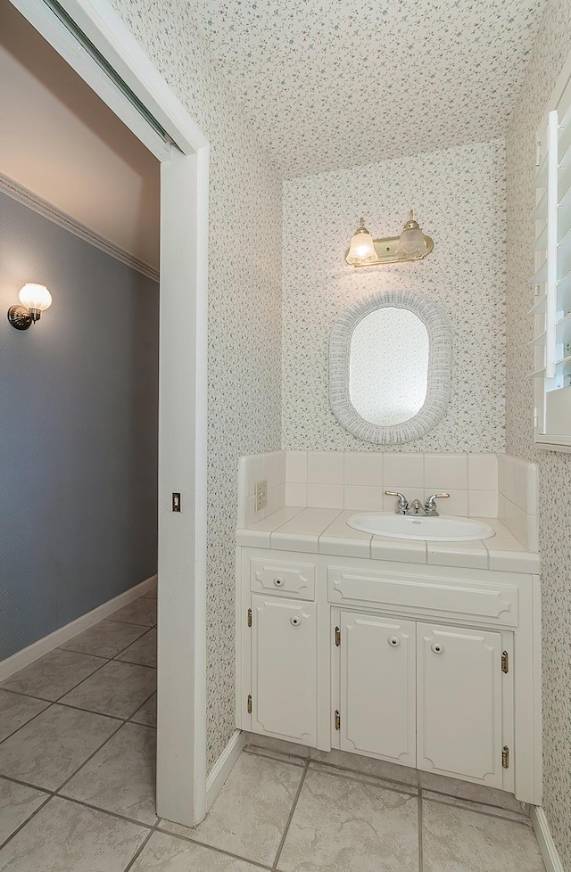 bathroom with vanity, baseboards, tile patterned floors, and wallpapered walls