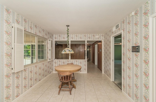 dining room with baseboards, light tile patterned floors, and wallpapered walls