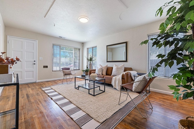 living area with wood-type flooring, a textured ceiling, and baseboards