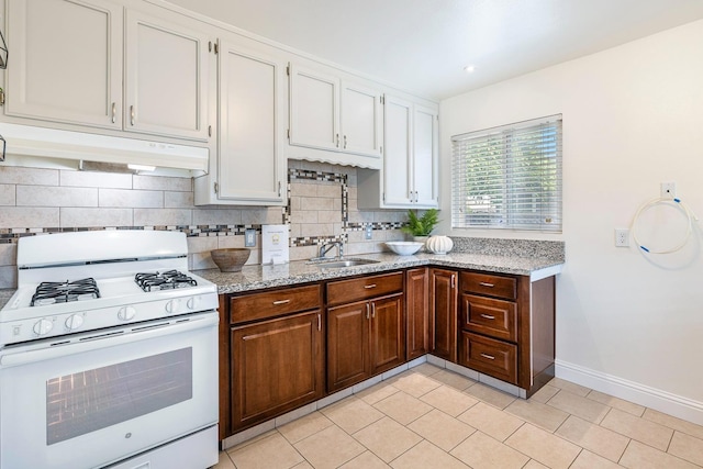 kitchen featuring backsplash, baseboards, a sink, and white gas range