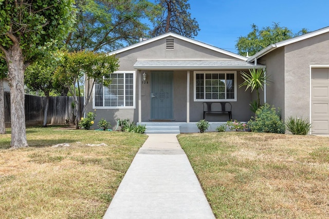 view of front of property featuring fence, covered porch, stucco siding, and a front lawn