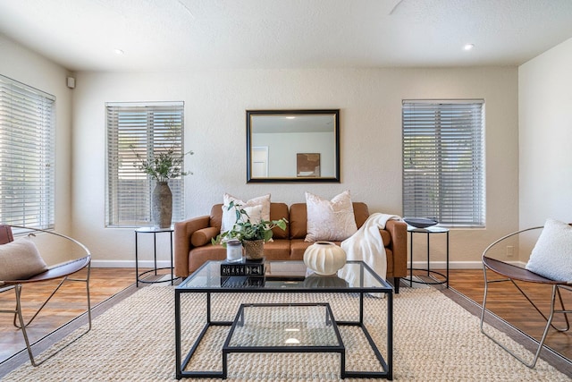 living area with baseboards, a textured wall, and wood finished floors