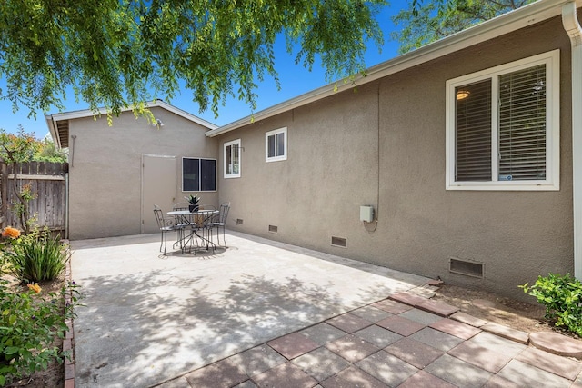 back of house featuring crawl space, fence, a patio, outdoor dining space, and stucco siding