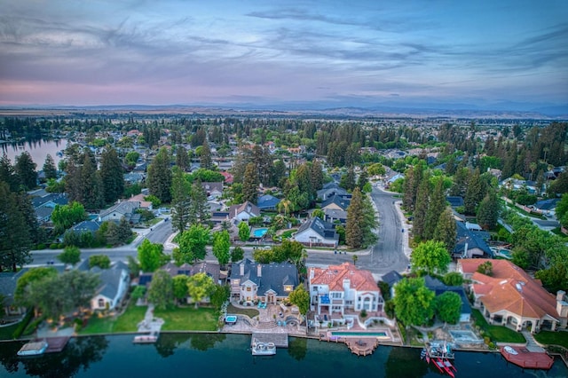 aerial view at dusk featuring a water view and a residential view