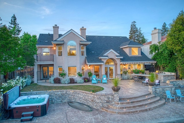 back of house with a balcony, a patio, french doors, outdoor dry bar, and a hot tub