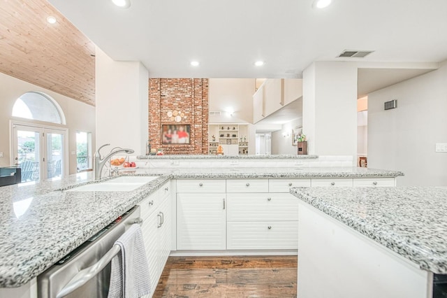 kitchen featuring dark wood-style flooring, light stone countertops, a sink, dishwasher, and visible vents