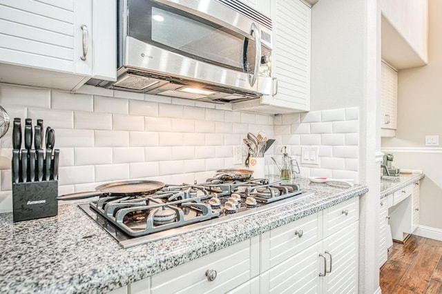 kitchen featuring white cabinets, dark wood-style flooring, stainless steel microwave, decorative backsplash, and gas stovetop