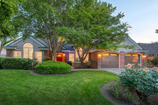 view of front of property with a lawn, an attached garage, concrete driveway, and brick siding