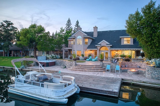 back of house with roof with shingles, a chimney, a balcony, a patio, and a fire pit