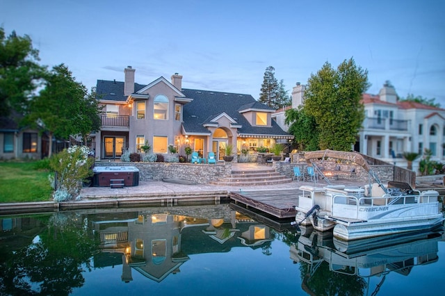 back of property featuring a chimney, a hot tub, and a balcony