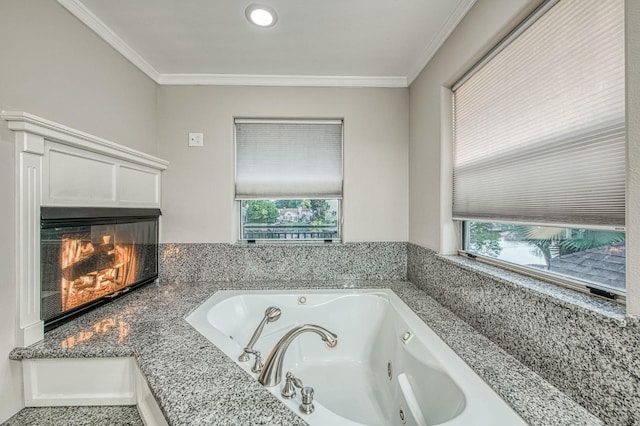 bathroom featuring a glass covered fireplace, ornamental molding, and a jetted tub