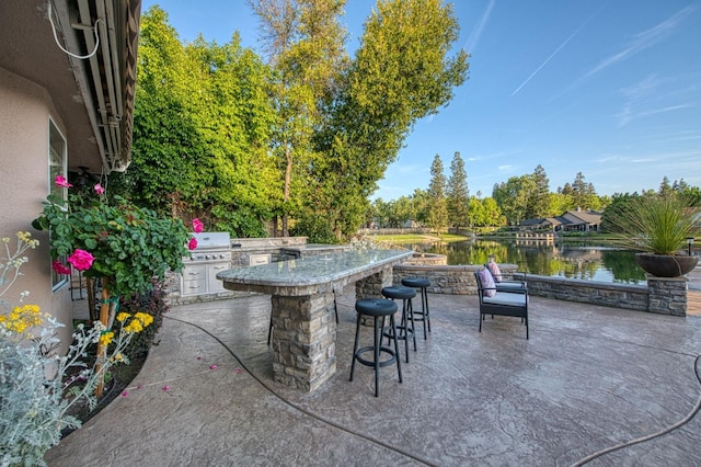 view of patio featuring exterior kitchen, a grill, a water view, and outdoor wet bar