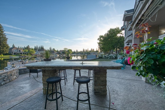 view of patio with outdoor dry bar and a water view