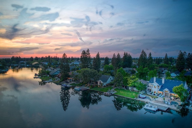 aerial view at dusk featuring a water view and a residential view