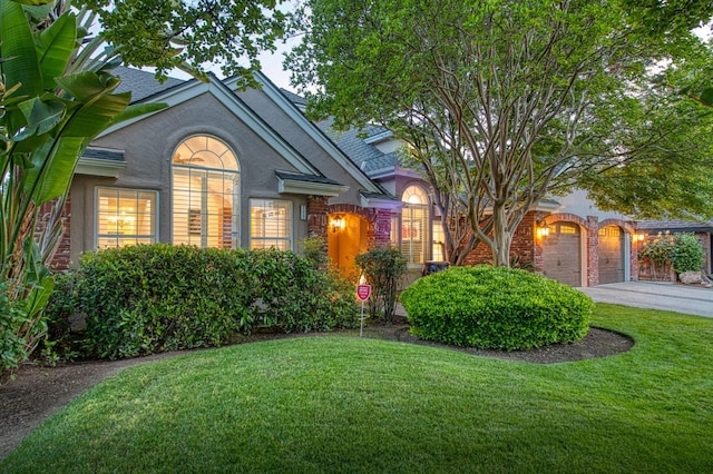view of front of property featuring stucco siding, driveway, a front yard, and a garage