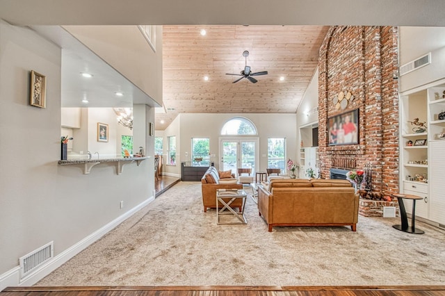 living area featuring baseboards, visible vents, ceiling fan with notable chandelier, and a fireplace