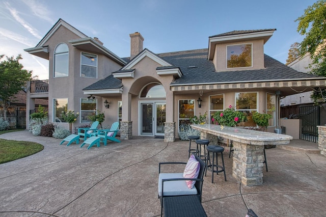 back of property featuring a patio, outdoor dry bar, and roof with shingles