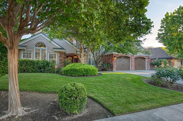 obstructed view of property featuring a garage, stucco siding, driveway, and a front yard