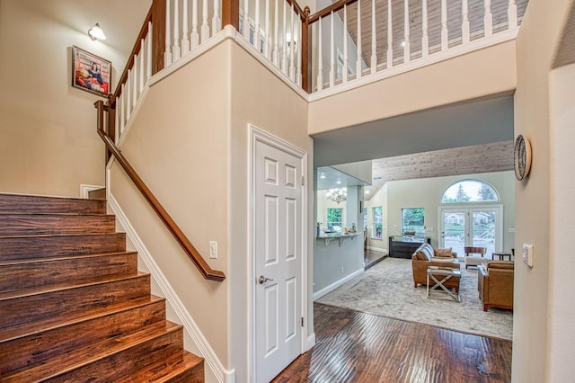 stairway with baseboards, a high ceiling, and wood finished floors