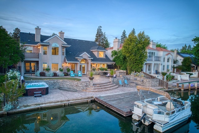 back of house featuring french doors, a patio, a chimney, and a hot tub