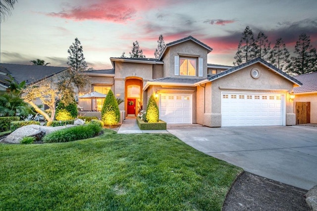 traditional-style house featuring stucco siding, a yard, and concrete driveway
