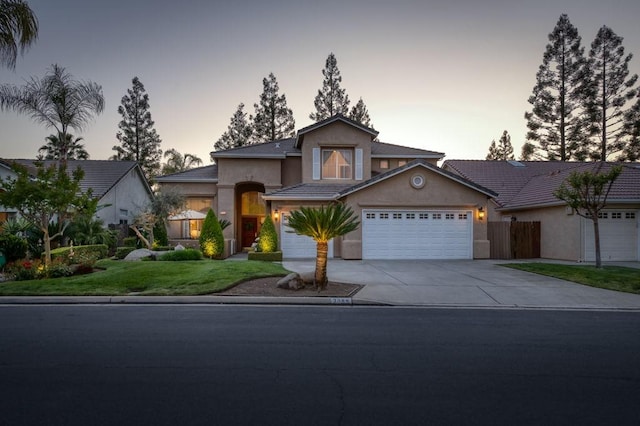 traditional-style home featuring concrete driveway, a garage, a front yard, and stucco siding
