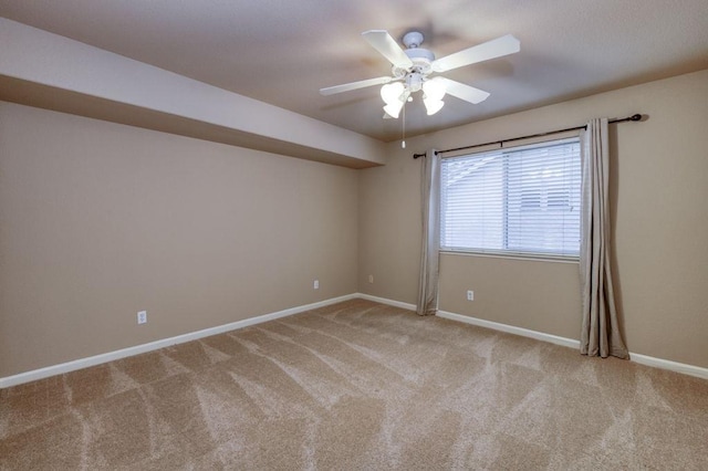 carpeted spare room with ceiling fan and baseboards