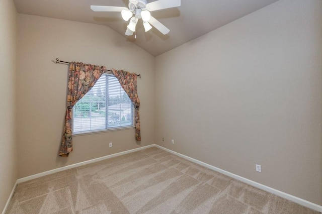 empty room featuring carpet floors, baseboards, ceiling fan, and vaulted ceiling