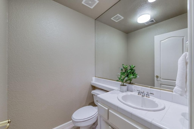 bathroom featuring a textured wall and visible vents