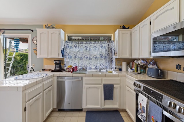 1215 Fremont Ave, Clovis, CA 93612 - kitchen with white cabinets, appliances with stainless steel finishes, a sink, tile countertops, and a peninsula
