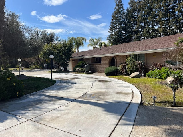 single story home featuring curved driveway and brick siding