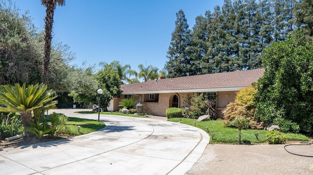 single story home with curved driveway and a chimney
