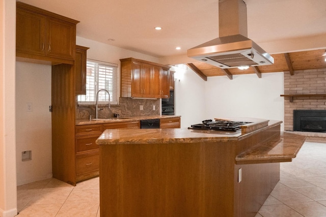 kitchen featuring brown cabinetry, island range hood, tasteful backsplash, a sink, and light tile patterned floors