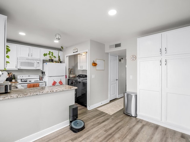 kitchen with light wood-style floors, washing machine and dryer, white appliances, and white cabinetry