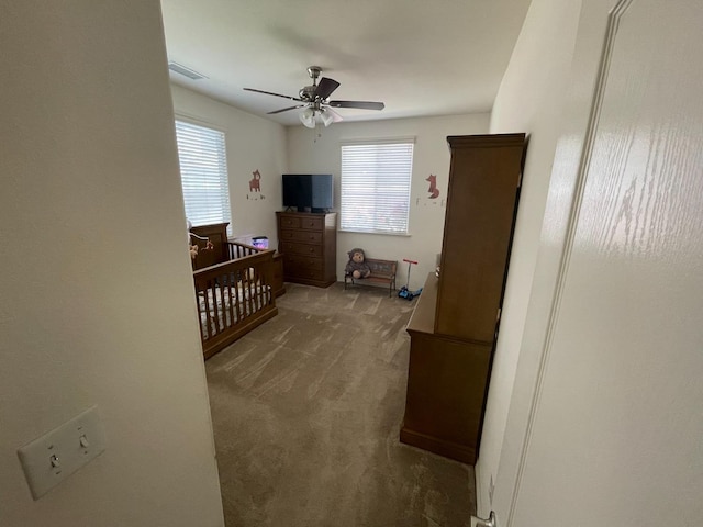 bedroom with carpet floors, a ceiling fan, a crib, and visible vents